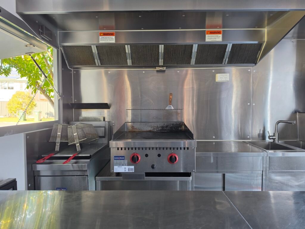 Stainless steel mobile kitchen fitout inside a food trailer showing gas griddle and fryer connected by LTC Gas